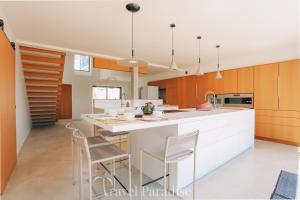 a kitchen with a white counter and wooden cabinets at Villa Saint Exupery in Le Bois-Plage-en-Ré