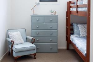 a bedroom with a dresser and a chair next to a bed at Kiki's Beach House in Durras