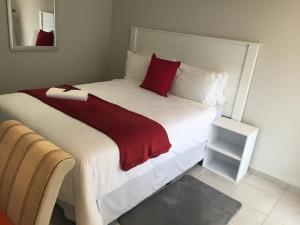 a bedroom with a large bed with red pillows at Carnival View Guest Lodge and spa in Boksburg