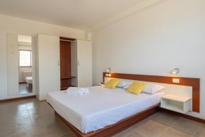 a bedroom with a large white bed with yellow pillows at Las Rochas Mindelo Aparthotel in Mindelo +44 photos