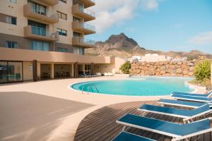 a hotel with a swimming pool and lounge chairs at Las Rochas Mindelo Aparthotel in Mindelo