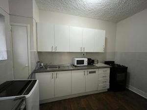 a kitchen with white cabinets and a microwave at Robridon in Summerstrand +1 photo