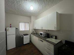 a kitchen with white cabinets and a white refrigerator at Robridon in Summerstrand