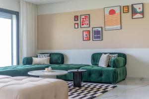 ein Wohnzimmer mit 2 grünen Sofas und einem Tisch in der Unterkunft The lodge Residence by Goodmove - Hay Riad in Rabat