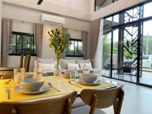 a dining room table with a vase of flowers on it at Ploy Mountain View Pool Villa in Ban Thai Thai