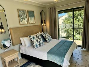 a bedroom with a bed with pillows and a balcony at Settler Sands - Holsboer Vacations in Port Alfred