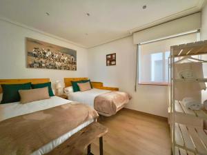 Un dormitorio con dos camas y una ventana. en Lindo pisito, en León