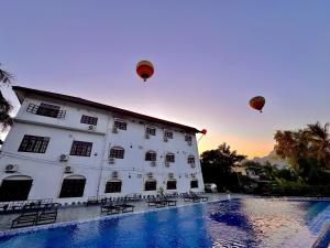 two hot air balloons are flying over a building at Jungle Backpackers View in Vang Vieng
