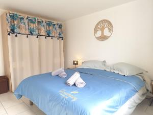 a bedroom with a blue bed with towels on it at Le Jardin des Mazades - Cosy T2 - Parking - Wifi Fibre Gratuit in Champcevinel