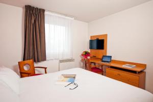 a hotel room with a bed and a desk with a laptop at Séjours & Affaires Bordeaux de L'Yser in Bordeaux
