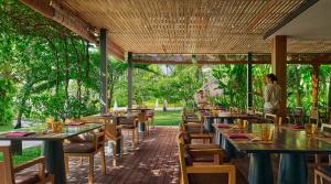 a woman standing in a restaurant with tables and chairs at PARKROYAL Penang Resort in Batu Ferringhi +70 photos