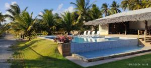 ein Pool mit Stühlen und ein Resort in der Unterkunft Mansão Ponta da Asa in Coruripe