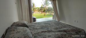 ein Schlafzimmer mit einem Bett und einem großen Fenster in der Unterkunft Mansão Ponta da Asa in Coruripe