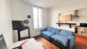 a living room with a blue couch and a kitchen at Vue sur Jardin - Netflix - Stationnement gratuit in Migennes