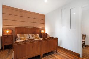 une chambre avec un lit en bois et deux tables de nuit dans l'établissement Appartamento Buthier Aosta, à Aoste