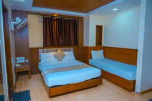 a small bedroom with two beds and a window at Octave Hotel AM Garden in Bangalore