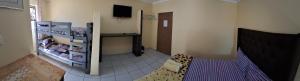 a room with a bed and a tv on a wall at Supa Guesthouse in Parow