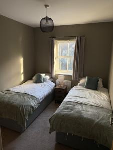 a bedroom with two beds and a window at Spacious Contractor House for Families, Groups, and Free Parking in Yeovil