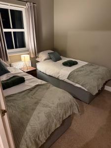 a bedroom with two beds and a window at Spacious Contractor House for Families, Groups, and Free Parking in Yeovil