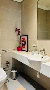 a bathroom with a sink and a toilet and a mirror at MontRose residence Tower A 1BR Apartment in Dubai