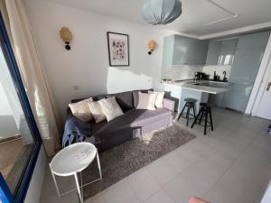 a living room with a couch and a kitchen at Sunny Seaview Modern apt - pool and beach access in Taurito