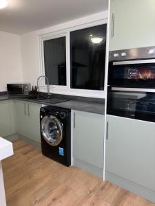 une cuisine avec un lave-linge et un micro-ondes dans l'établissement House-Sleeps8-Parking-Garden, à Leeds