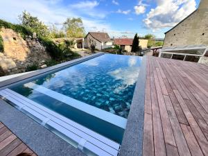 a swimming pool with a wooden deck at Gîte - petite maison proche du Futuroscope in Beaumont