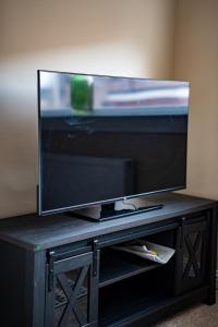 TV de pantalla plana en un centro de entretenimiento negro en Skye House, en Grangemouth