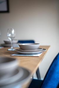 a wooden table with plates and a glass on it at Skye House in Grangemouth +32 photos
