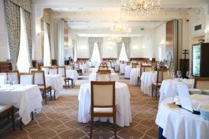 a restaurant with white tables and chairs and a chandelier at BRISTOL Hotel Opatija in Opatija