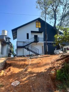 a house with a black roof on a dirt road at The Tea Leaf Cottage in Munnar