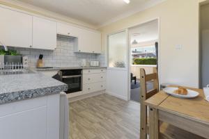 a kitchen with white cabinets and a wooden table at Leconfield Close - Comfy house and free parking in Hull