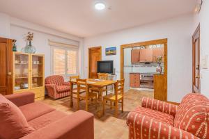 een woonkamer met een tafel en stoelen en een keuken bij Apartamentos Haza La Moraleda 2 y A in Güéjar-Sierra