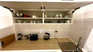 a kitchen with white shelves with dishes on it at Apartment Mauerblick in der Altstadt mit Smart TV Waschtrockner und voll ausgestatteter Küche in Goslar