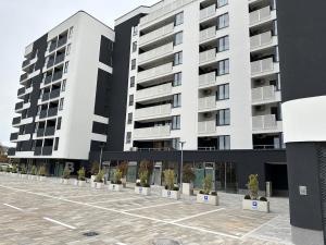 a large white building with potted plants in a parking lot at New apartment in Sarajevo