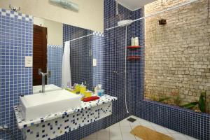 uma casa de banho em azulejos azuis com um lavatório e um chuveiro em Toca do Jacaré em Granja Beira Mar