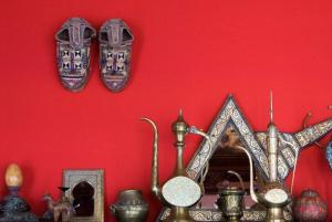 einer roten Wand mit Platten und anderen Gegenständen auf einem Regal in der Unterkunft Riad La Terrasse Des Oliviers in Marrakesch