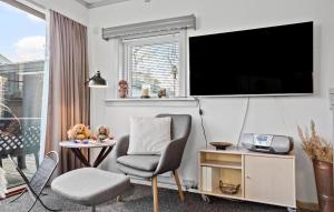 a living room with a chair and a tv on a wall at Holiday Home Vestre Strandvej Nexø Iii in Balke