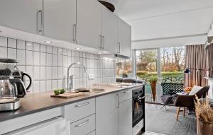 a white kitchen with a sink and a stove at Holiday Home Vestre Strandvej Nexø Iii in Balke