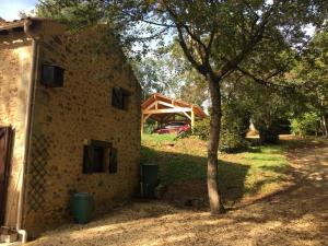 ein Steingebäude mit einem Baum daneben in der Unterkunft Le coustal in Le Clapier