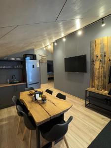 een eetkamer met een houten tafel en een flatscreen-tv bij Mine Hostel Dzhergalan in Dzhergalan