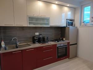 a kitchen with red cabinets and a sink and a refrigerator at Apartment Fontana in Buzet