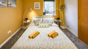 a large bed with two yellow pillows on it at Sunny day new flat with 5 beds in Clydebank