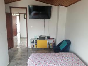 a bedroom with a bed and a tv on the wall at HABITACIONES CASA CAMPESTRE Duitama in Duitama