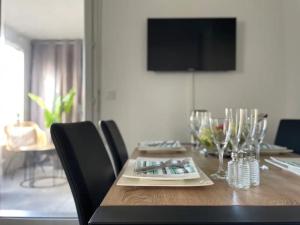 a dining room table with chairs and a television on the wall at AJ - Stylish Pied-à-Terre à La Joliette - Parking in Marseille