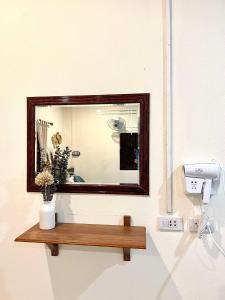 a mirror on a wall with a wooden shelf at Khao Sok Green Mountain View in Khao Sok National Park