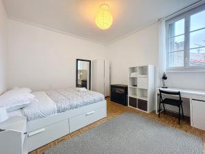 una camera da letto bianca con un letto e una scrivania di Hyper-centre apartment Treille 29 a Clermont-Ferrand