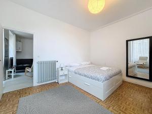una camera da letto bianca con un letto e uno specchio di Hyper-centre apartment Treille 29 a Clermont-Ferrand