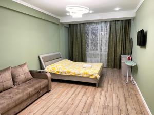 un salon avec un lit et un canapé dans l'établissement Vavilon, à Bishkek