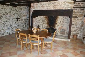 a wooden table and chairs in a room with a fireplace at La Maison de Louise in Altillac